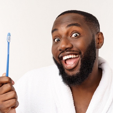person smiling and holding a toothbrush