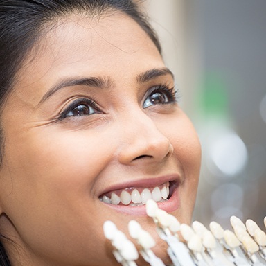 Woman's smile compared with tooth color chart