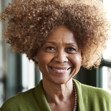 person smiling and standing in front of a window