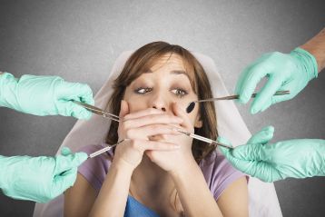 Woman at the dentist covering her mouth in fear